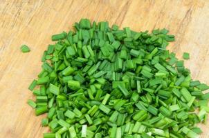 A chopped green onions on a wooden chopping board photo