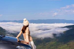 Young woman travelers with car watching a beautiful sea of fog over the mountain while travel driving road trip on vacation photo