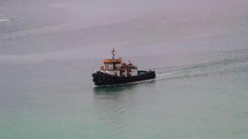 Tugboat or marine vessel that maneuvers vessels by pushing or towing them travel at the sea. photo