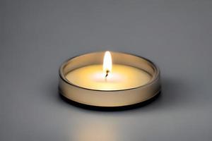 An isolated candle in a glass plate on grey background. Aromatherapy candle. photo