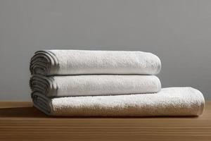 Clean white folded towel nice and tidy stack each other at the table for fitness, bath, swimming, massage and spa marketing background and design material isolated on grey background. photo