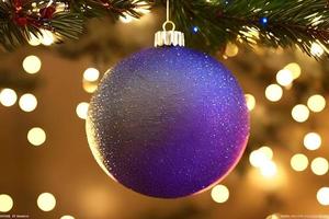 Hanging glimmering purple ball Christmas ornament decoration at the Christmas tree. Background for seasonal greetings.