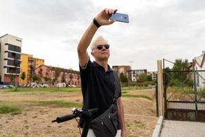 viajero diario al trabajo hipster hombre con eléctrico scooter tomar un selfie con teléfono inteligente foto