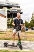 Commuter hipster man is using electric scooter on the outskirts of a city photo