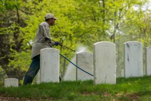 Washington DC, EE.UU. - 2 de mayo de 2014 - el trabajador está limpiando lápidas en el cementerio de Arlington foto