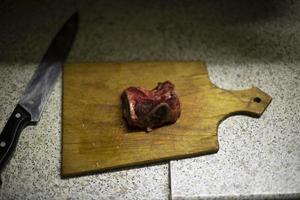 Meat on kitchen board. Knife and piece of raw meat. Food on table. photo