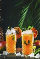 alcohólico cóctel con vodka, piña jugo, mango, espíritu, hielo. largo bebida o verano cóctel sin alcohol tropical oscuro antecedentes con palma hojas y exótico frutas