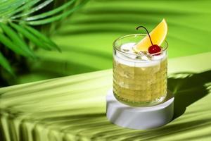 whisky agrio alcohólico cóctel con Borbón, limón jugo, huevo blanco y hielo, rocas vaso en brillante verde antecedentes con difícil ligero y oscuridad foto