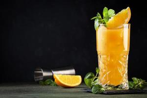 destornillador, clásico alcohólico cóctel con vodka, naranja jugo y hielo, adornado con Fruta rebanada y menta. oscuro fondo, bar herramientas
