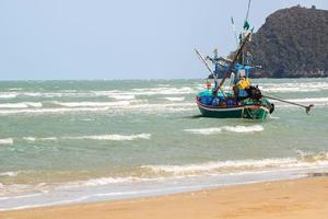 Small fishing boats are mooring at the coast and selling the marine animals they find at The seaside where the waves are always windy. The boat is made of hardwood throughout the hull. photo