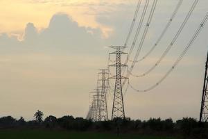 High-voltage poles are used to carry electricity for industrial plants and people to use in the farmer's fields in the evening. Beautiful sky atmosphere and designed by electrical engineers. photo