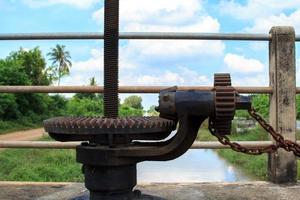 Hand-cranked water-gate for closing and opening water in irrigation canals for agriculture. Farmers' cultivation requires water for cultivation. photo