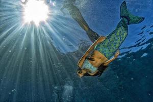 two Mermaid swimming underwater in the deep blue sea photo