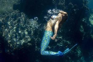 sirena nadando bajo el agua en el mar azul profundo foto