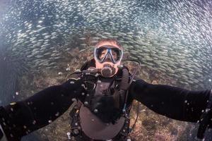 beautiful diver in fish and corals reef background photo