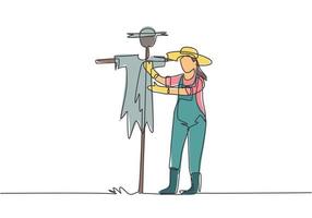 Single continuous line drawing a young female farmer in a straw hat putting up scarecrow to keep out pests of birds. Farming minimalist concept. One line draw graphic design vector illustration.