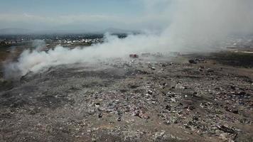 Drone flying over a smoking city dump. video