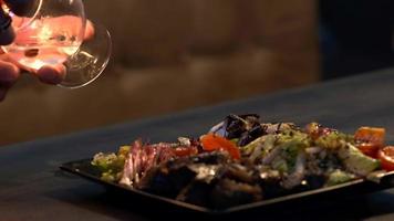 el barman luces un Sambuca en un vaso siguiente a un vegetal y carne bocadillo plato. de cerca. video