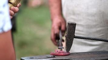 Close-up of forging a horseshoe. The blacksmith teaches the apprentice to knock on a red-hot horseshoe with a hammer. Training in blacksmithing. video