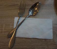 Fork with spoon and tissue paper on a wooden table in a cafe. photo