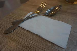 Fork with spoon and tissue paper on a wooden table in a cafe. photo