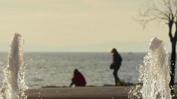två kvinna vän och sephia vinter- strand med fontän vatten droppar stänk video