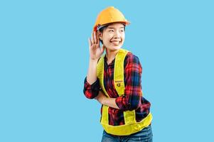 Young female engineer hand over ear to making hear gesture photo