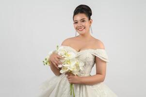 Young asian beautiful bride with orchid bouquet on white background photo