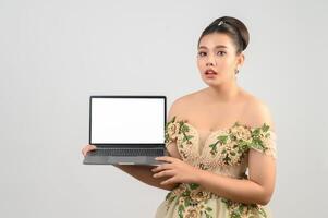 Young asian beautiful bride pose with mock up laptop computer in hand photo