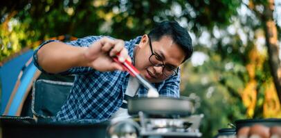 Portrait of Asian traveler man glasses frying a tasty fried egg photo