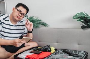 hombre asiático está preparando ropa en maletas foto