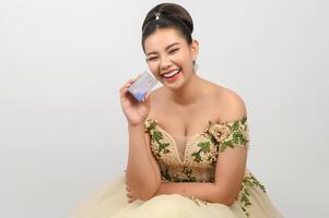 joven novia asiática hermosa publicando con tarjeta de crédito en la mano foto