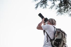 Asian traveler man with backpack taking a photo in the park