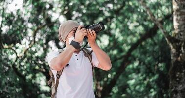 Asian traveler man with backpack taking a photo in the park