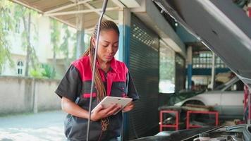 One Black female professional automotive mechanical worker checks an EV car battery and hybrid engine at a maintenance garage, expert electric vehicle service, and fixing occupations auto industry. video
