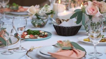 el camarera pone un plato de comida en un hermosamente decorado festivo mesa en rosado. video