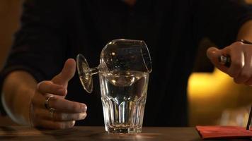 el barman luces el Sambuca en un vaso y vierte eso dentro otro. preparando cócteles a el bar. video