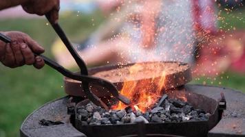 Close-up A blacksmith turns a molten red metal horseshoe over the fire with tongs. Blacksmithing craft. video