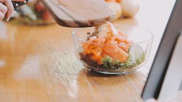 Young and happy woman eating healthy salad sitting on the table with green fresh ingredients indoors video