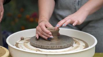 un' giovane ragazza con un' bellissimo manicure è apprendimento per rendere ceramica su un' di vasaio ruota. mani avvicinamento. video