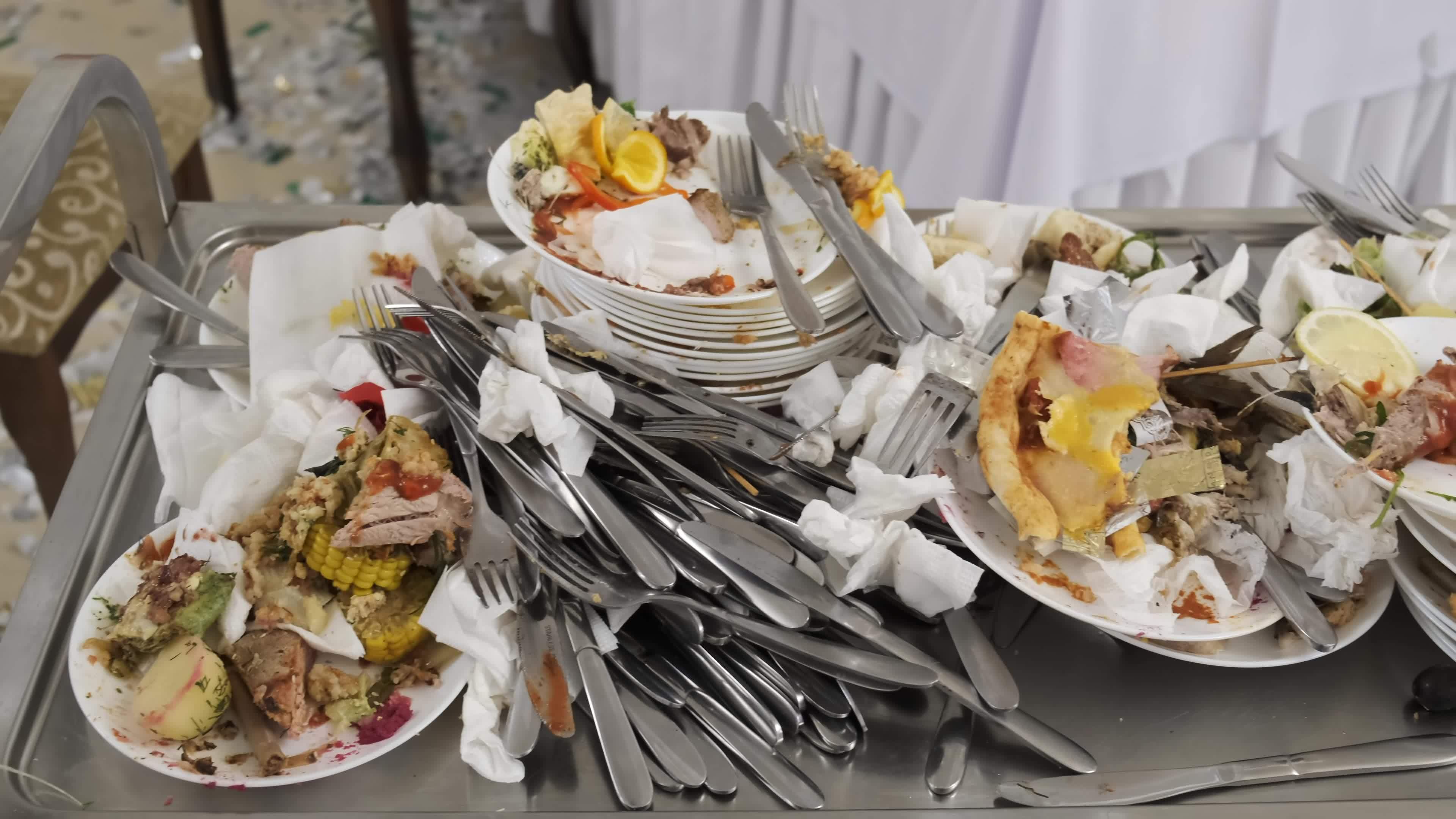 Leftovers from the banquet. Waiters collect dirty dishes on a cart. A