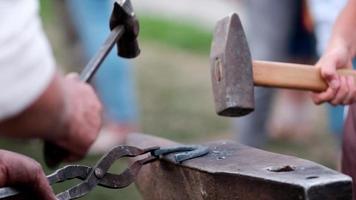 Close-up of forging a horseshoe. The blacksmith teaches the apprentice to knock on a red-hot horseshoe with a hammer. Training in blacksmithing. video