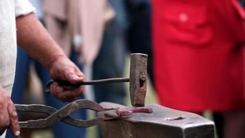 fechar-se do forjamento uma ferradura. a ferreiro ensina a Aprendiz para batida em uma vermelho quente ferradura com uma martelo. Treinamento dentro ferraria. video