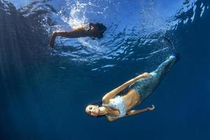 Mermaid swimming underwater in the deep blue sea photo