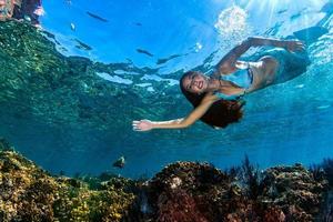 Mermaid swimming underwater in the deep blue sea photo