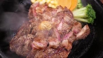 schließen oben gekocht von köstlich Lendenstück Steak serviert auf ein heiß schwenken Teller mit geröstet Gemüse und viele Rauch von Teller video