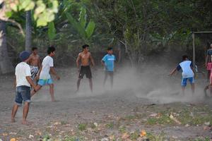 gili asahan, indonesia - 22 de agosto de 2016 - los niños juegan al fútbol al atardecer en un campo de palmeras cerca de la playa foto