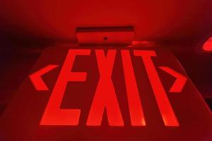 A red Exit sign. Emergency exit direction indicator on the ceiling in administrative building. Exit warning indicator for public safety in case of emergency photo