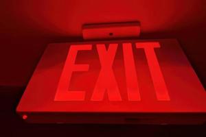 A red Exit sign. Emergency exit direction indicator on the ceiling in administrative building. Exit warning indicator for public safety in case of emergency photo