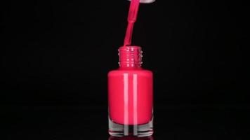 Pink neon nail polish on black background video